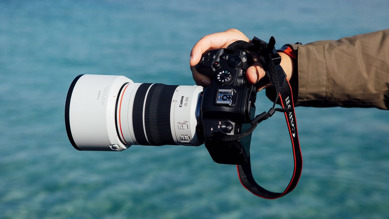 Objektív RF 70-200mm F4L IS USM a fotoaparát EOS R5, ktoré drží Lucia Griggi v jednej ruke, v pozadí more
