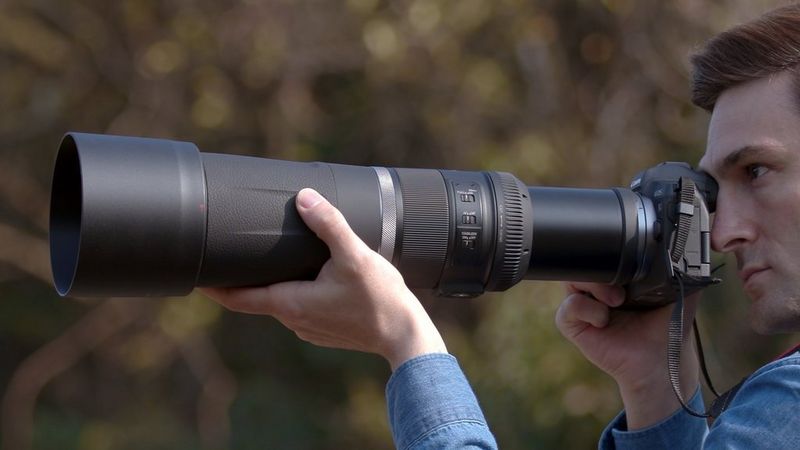 Person holding a Canon camera with a telephoto lens.