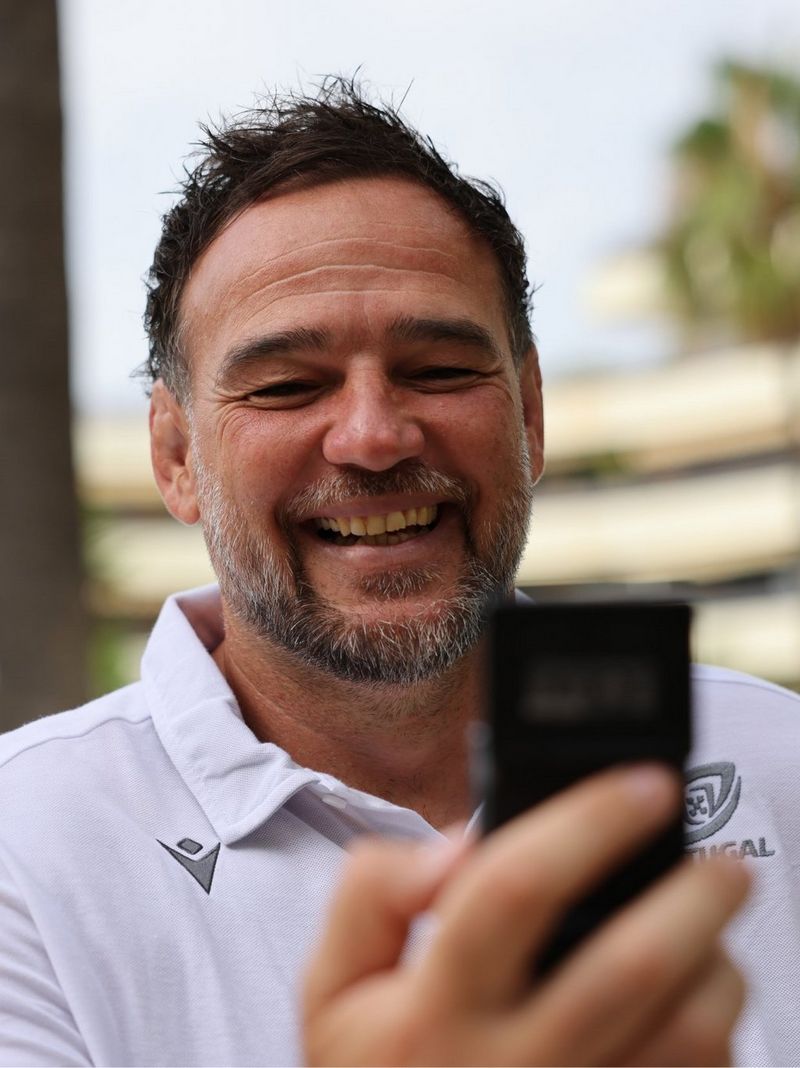 David smiles while looking at a mobile phone