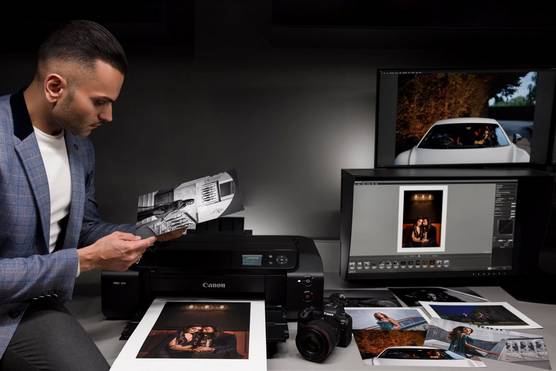 Photographer Sanjay Jogia studies an image printed by a Canon imagePROGRAF PRO-300. On the desk in front of the printer are several other prints.