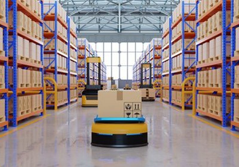 A 3D illustration of a warehouse, with shelves on left and right stacked high with brown cardboard boxes. Moving down the middle, between the shelves, is a yellow and black flat robot with a box on top of it, being transported down aisle.