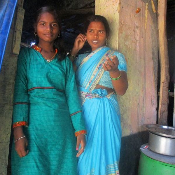 Two women in saris, stood in a doorway.