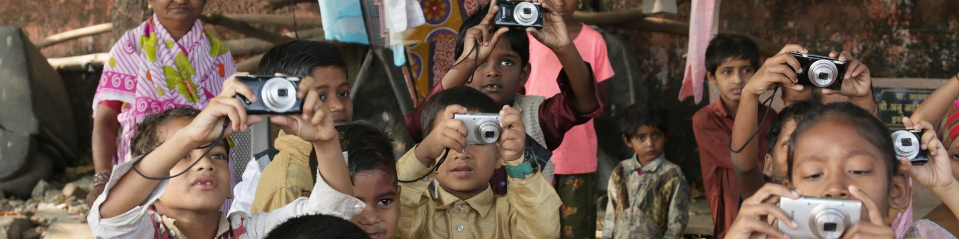  Little children in a group, holding their Canon cameras up to take a photo.