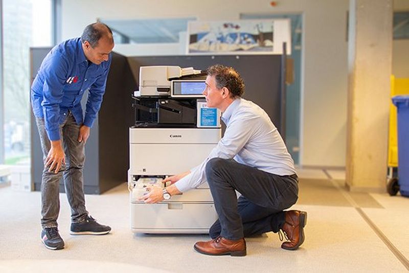 Canon engineer legt schoonmaker uit hoe hij een probleem moet oplossen bij de printer