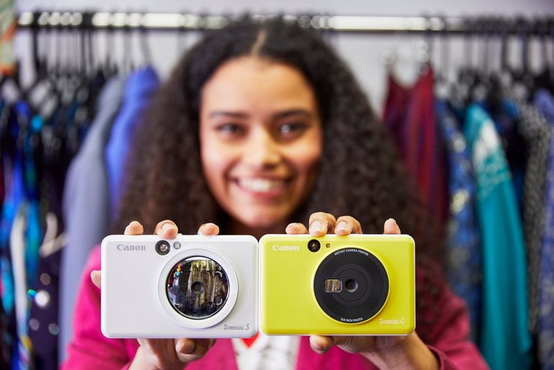 A woman holding a Canon Zoemini S in one hand and a Canon Zoemini C in the other.