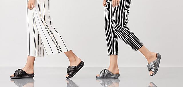Two models wearing Loosh Luxe sequin Cross slide Sandals, shown in colours Silver and Black.