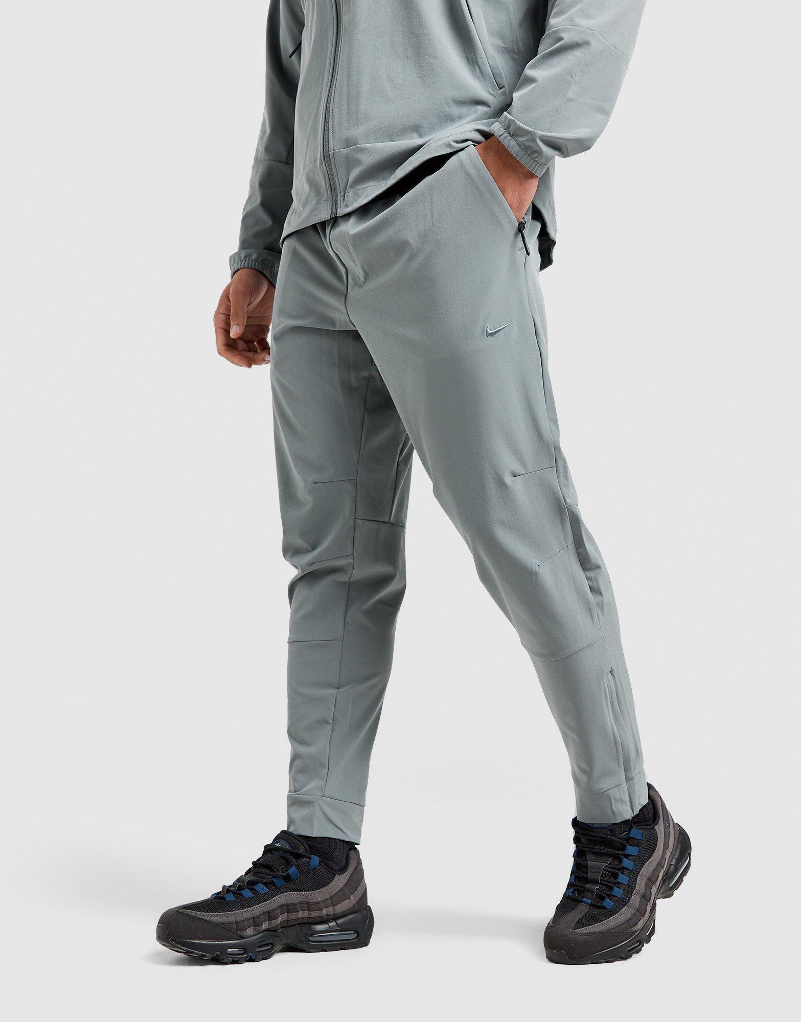 Мъжко фитнес облекло NIKE ПАНТАЛОНИ M NK DF UNLIMITED PANT TPR FB7548-084 Сив