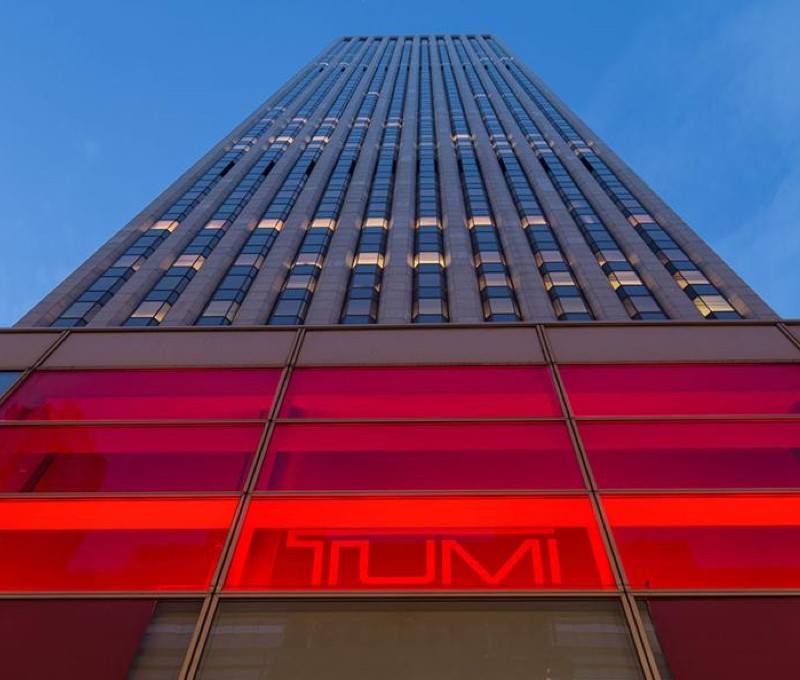 Tumi store building in the evening with red-lit sign.